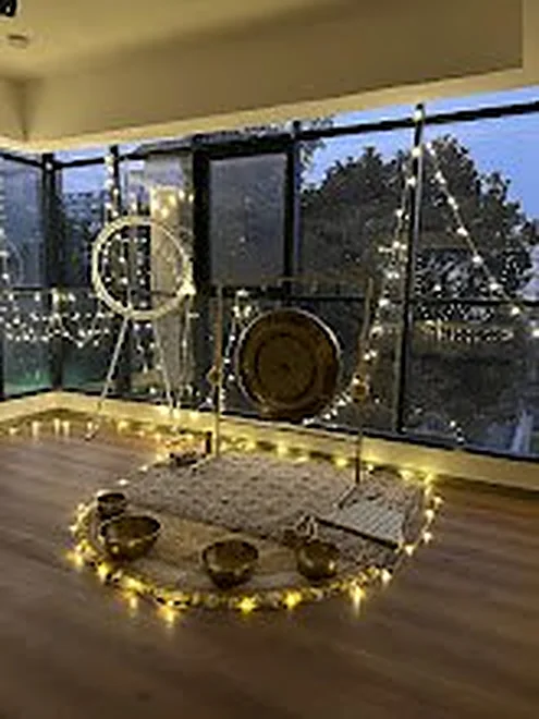 Sound bath setup with gong and fairy lights by the window
